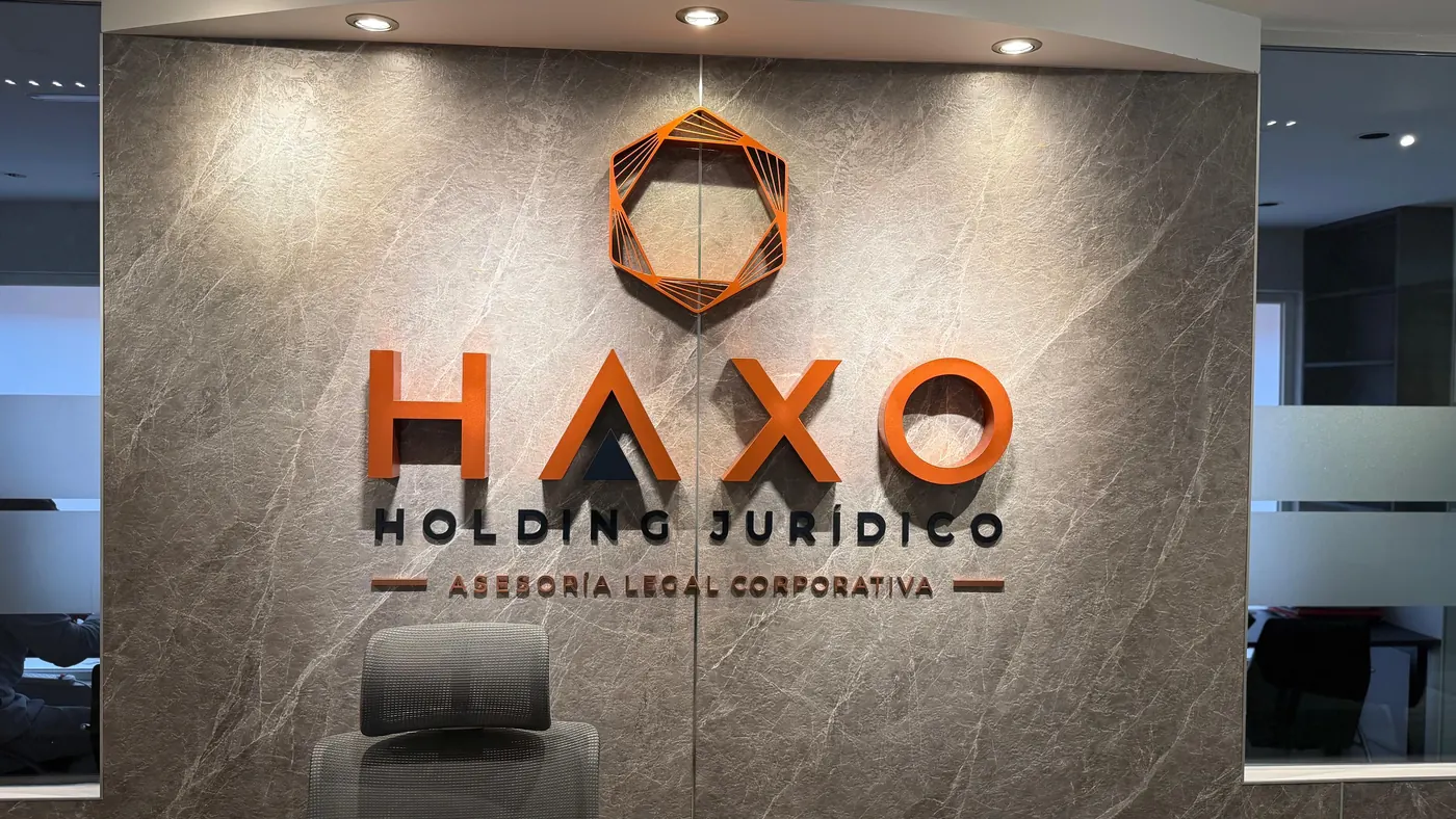 Rótulo de HAXO Holding Jurídico en la pared de mármol de la recepción