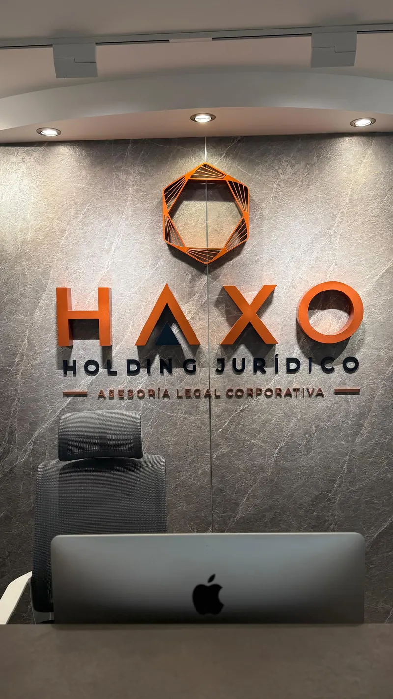 Rótulo de HAXO Holding Jurídico sobre la pared de mármol de la recepción