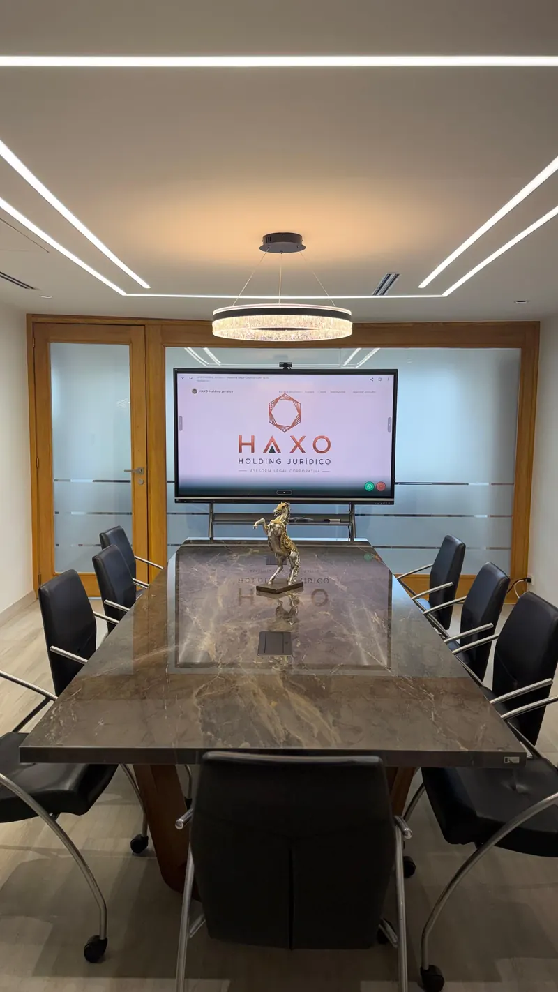 Sala de juntas con el logotipo de HAXO en pantalla y mesa de mármol