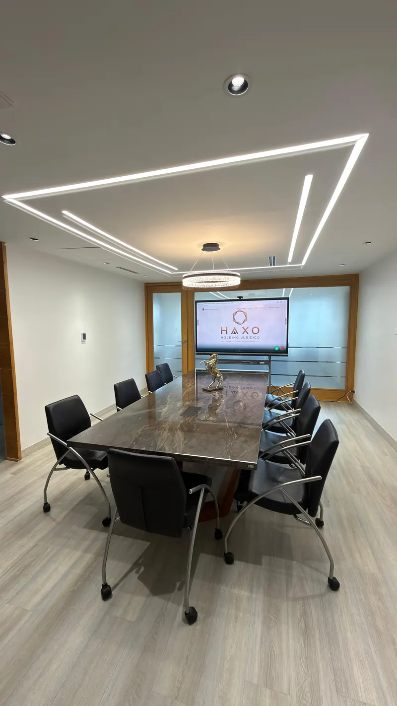 Sala de juntas con mesa para diez personas y pantalla de proyección