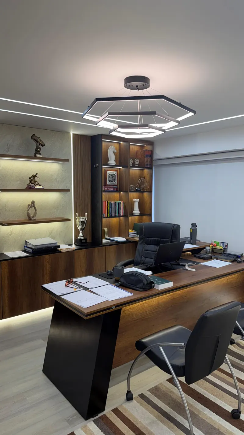 Despacho de socio con biblioteca iluminada y escritorio de madera